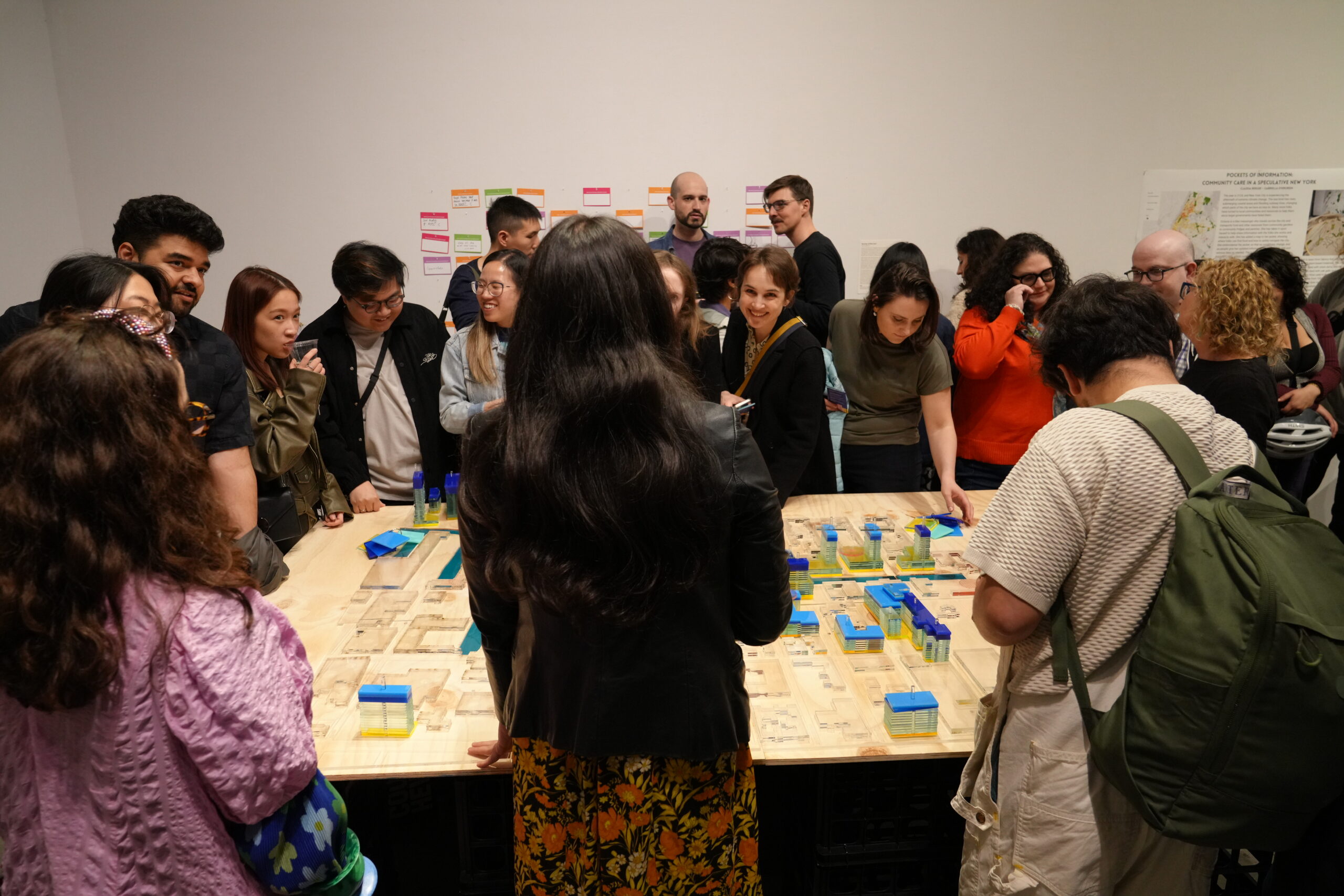 A group of people gather around Pockets of Information, one of the exhibition pieces at Data Through Design's Aftermath exhibition.