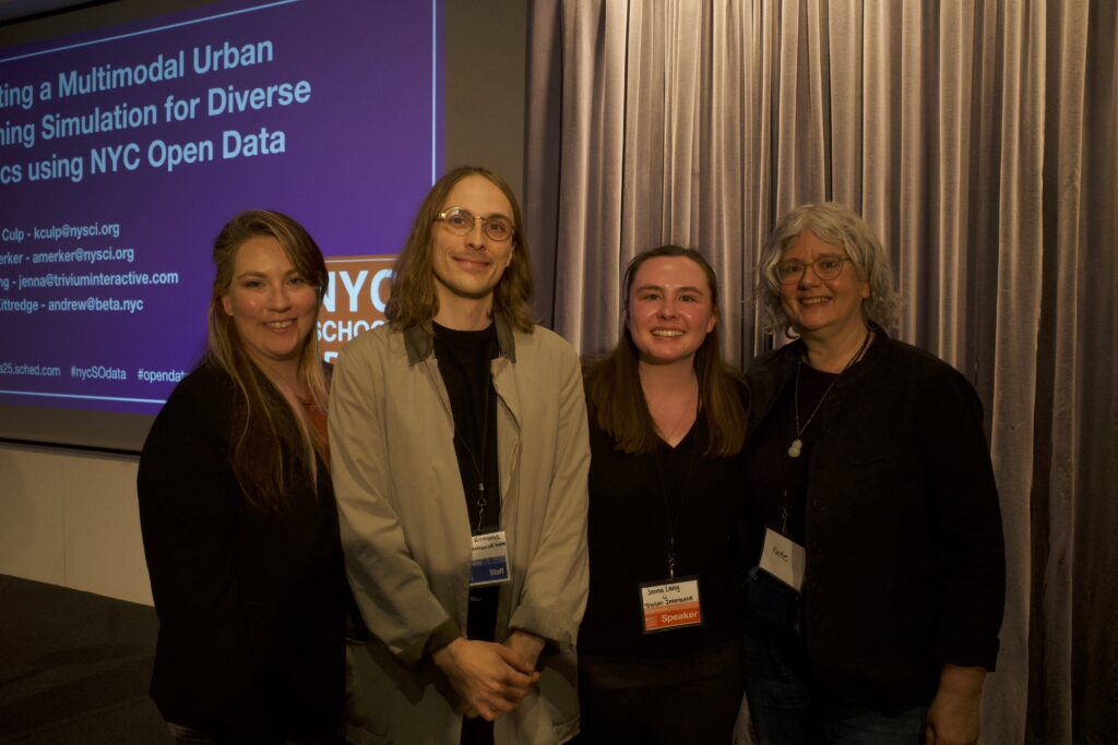 Four panelists stand together on stage in front of a projected NYC School of Data slide, smiling at the camera with gray curtains behind them.