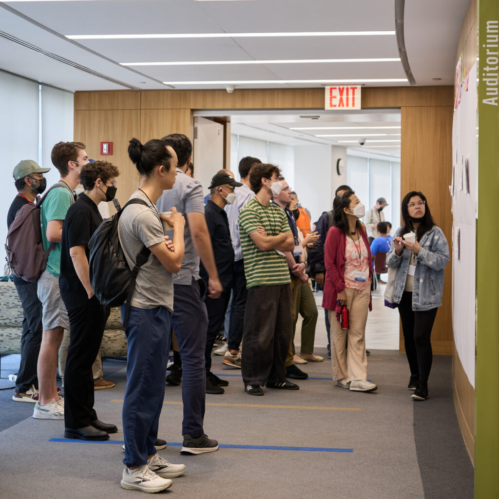 An image of a dozen CityCamp attendees looking intently at the proposals on the Session Pitch Wall