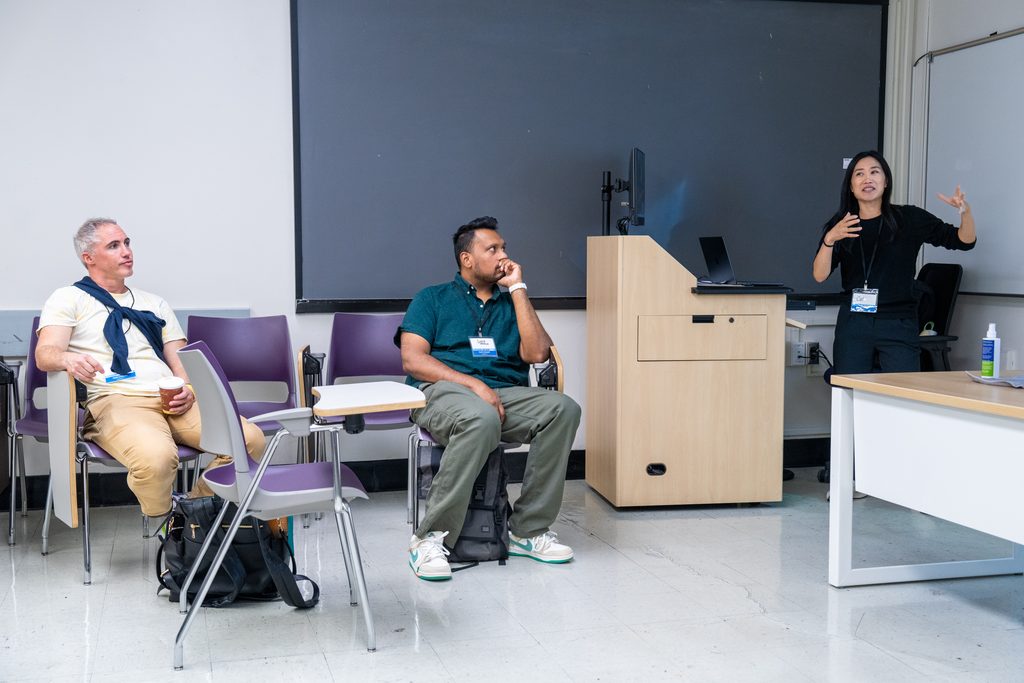 A session leader gestures while presenting to seated participants in a classroom.