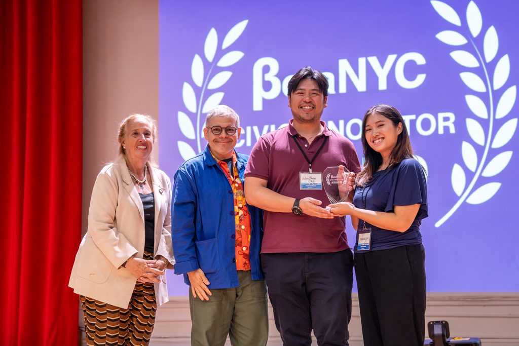 Four people pose on stage with a Civic Innovator Award in front of a BetaNYC Civic Innovator slide.
