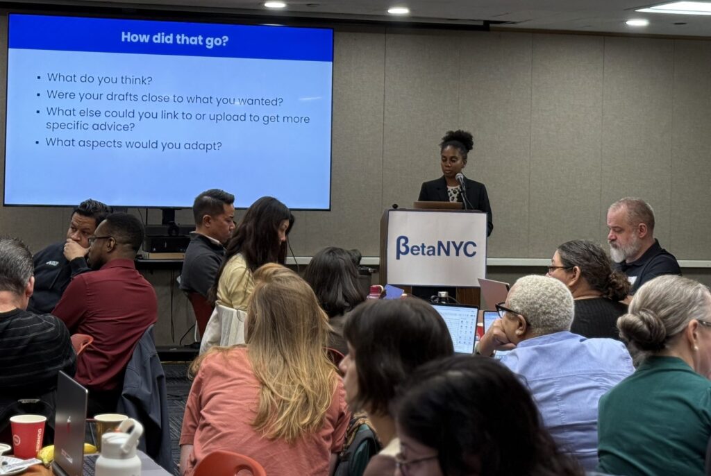 Gabrielle Langston leads a discussion about AI-generated drafts as workshop participants work at tables with laptops.