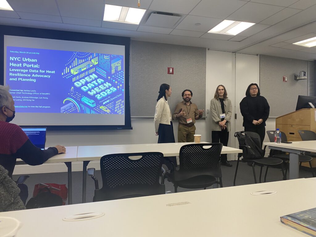 In a classroom-style conference room, four presenters stand at the front near a lectern while an “NYC Urban Heat Portal: Open Data Week 2025” slide is projected on the screen, with attendees seated at tables facing them.