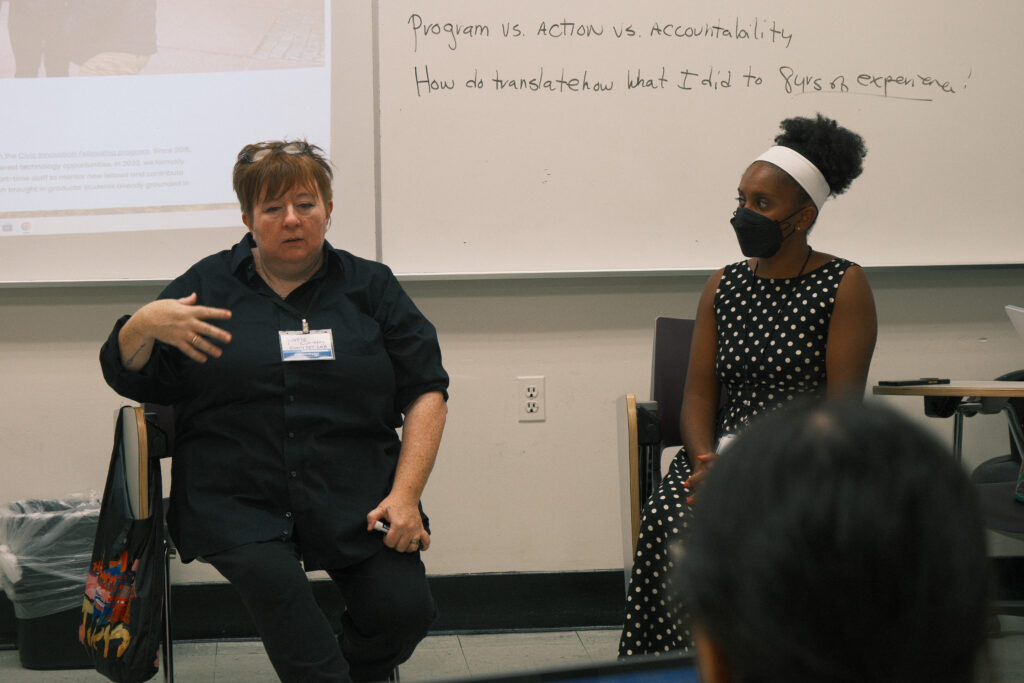 Two participants lead a discussion in front of a whiteboard about program, action, and accountability.