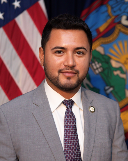 An image of Council Member Justin Sanchez wearing a grey jacket and white top.