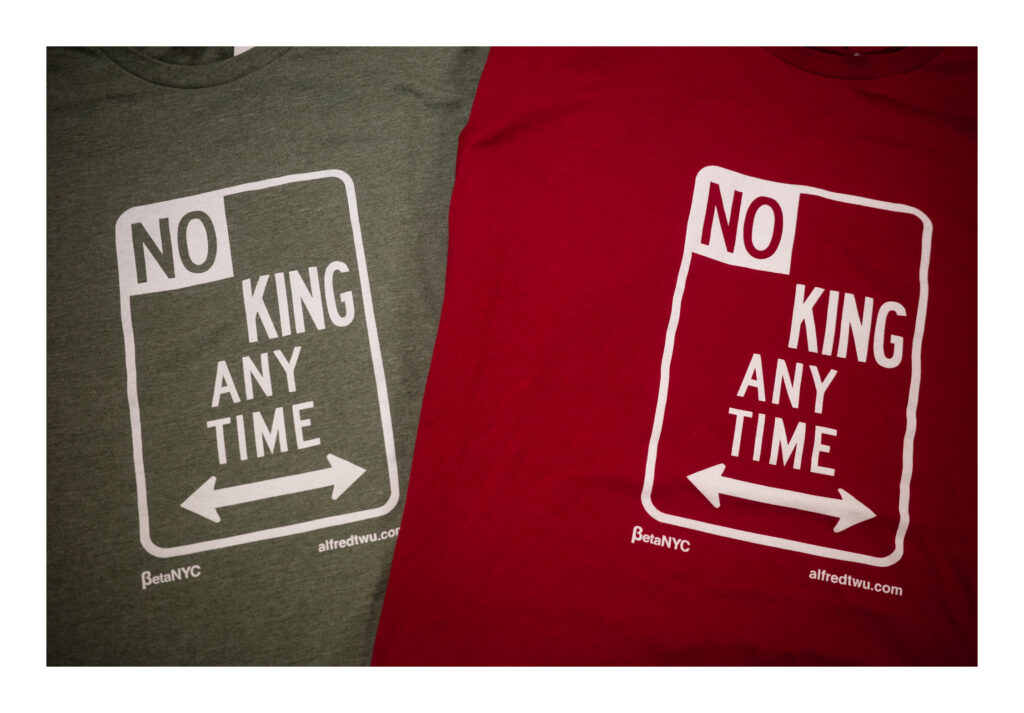 Two t-shirts lay side by side, one olive green and one deep red, featuring a bold white graphic that mimics a New York City parking sign. The design reads “NO KING ANY TIME” with double-headed arrows pointing left and right at the bottom. Below are the logos for BetaNYC and alfredtwu.com.